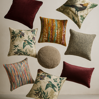 Assorted decorative cushions with various patterns and colors on a neutral background