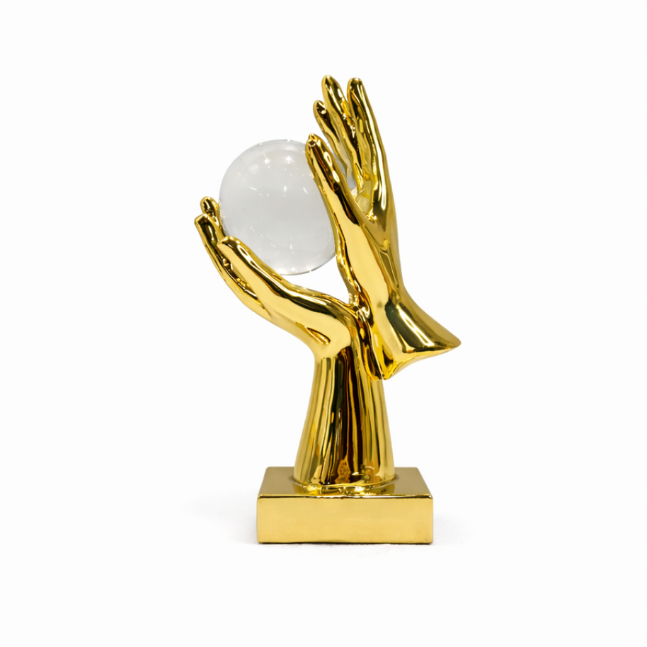 Gold-finish hands holding a clear crystal sphere on a white background.