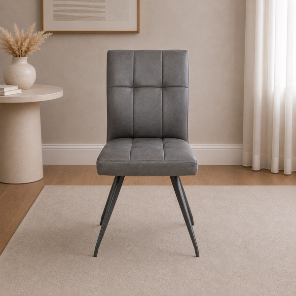 Gray upholstered chair in a room with a beige wall, small table, and decorative elements.