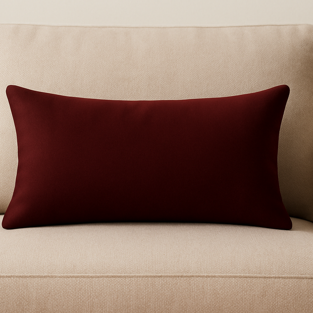 Beige sofa with a mulberry velvet cushion on a plain background