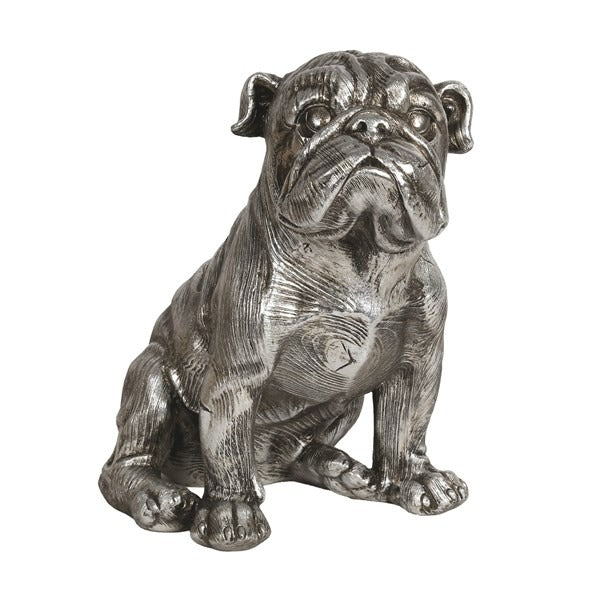 Silver-finish sitting bulldog sculpture with a sleek metallic surface, displayed on a modern grey tiled floor next to a tall plant.