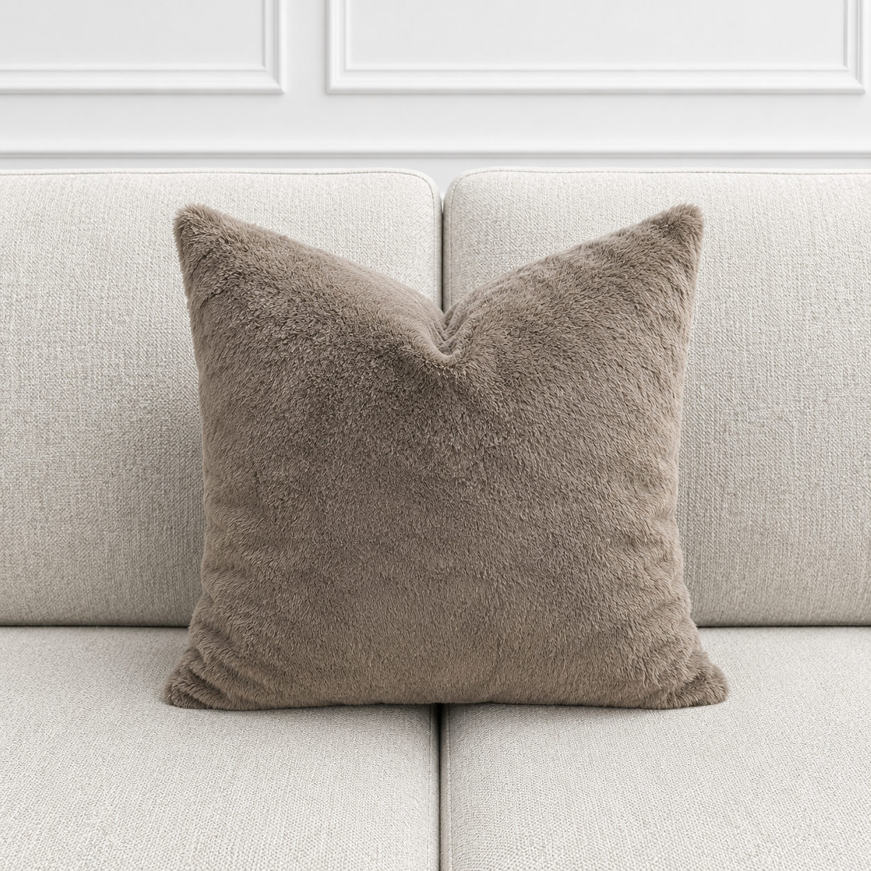 Brown pillow on a light gray sofa with a white paneled wall background