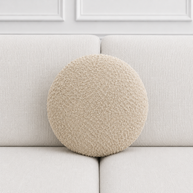 Round beige cushion on a light gray sofa