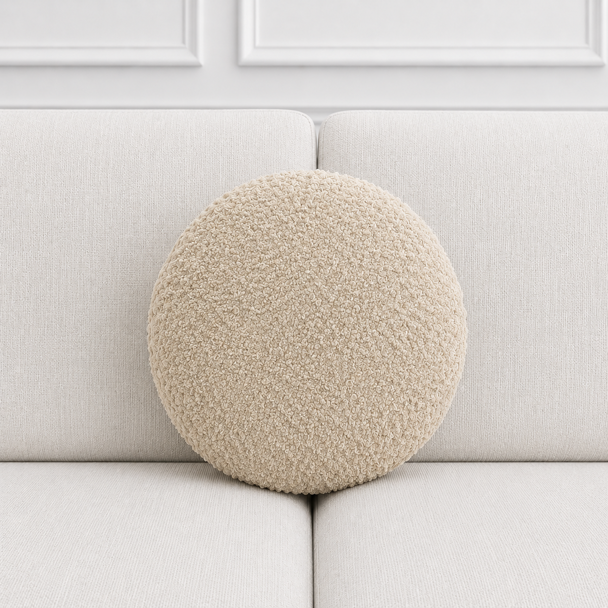 Round beige cushion on a light gray sofa