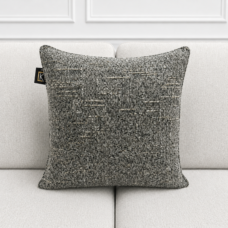 Textured gray pillow on a light gray sofa with a white wall background