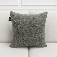 Textured gray pillow on a light gray sofa with a white wall background