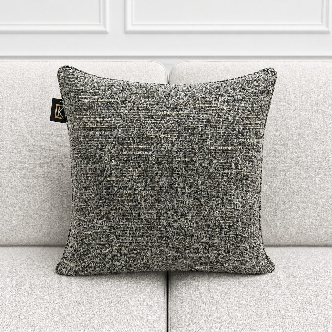 Textured gray pillow on a light gray sofa with a white wall background