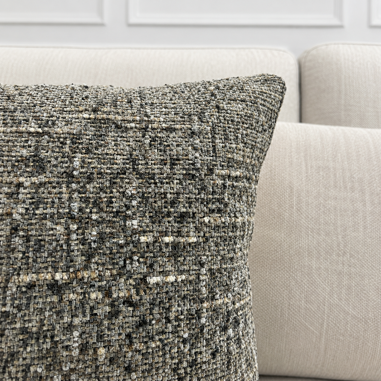 Textured throw pillow on a beige sofa with a neutral background