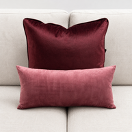 Two maroon pillows on a light gray sofa
