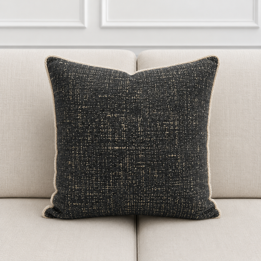 Textured black pillow on a light gray sofa with a neutral background
