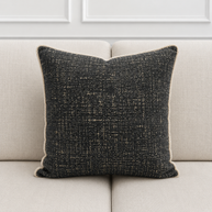 Textured black pillow on a light gray sofa with a neutral background