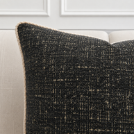 Textured black pillow on a light-colored sofa against a white wall.